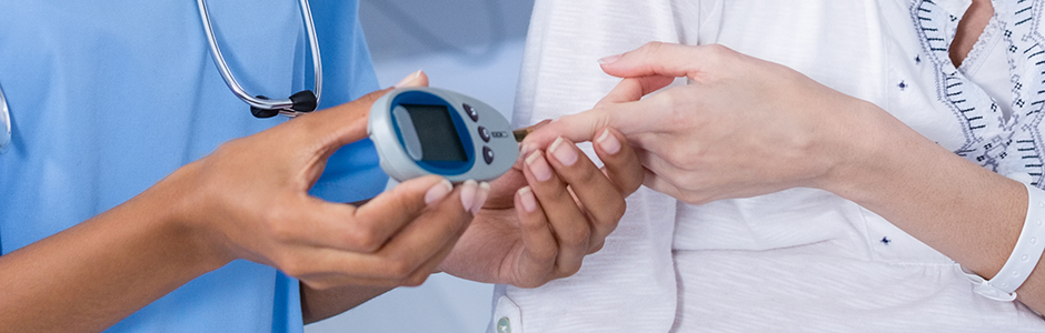 A physician helps a patient take their glucose reading.