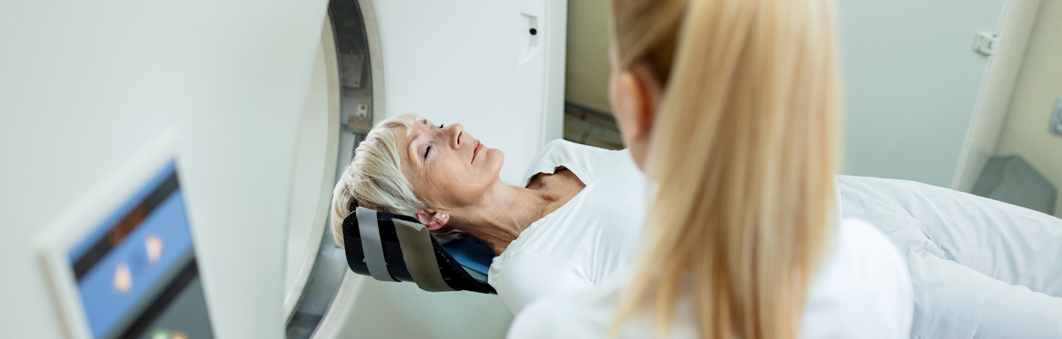 Technician overseeing CT scan for older woman