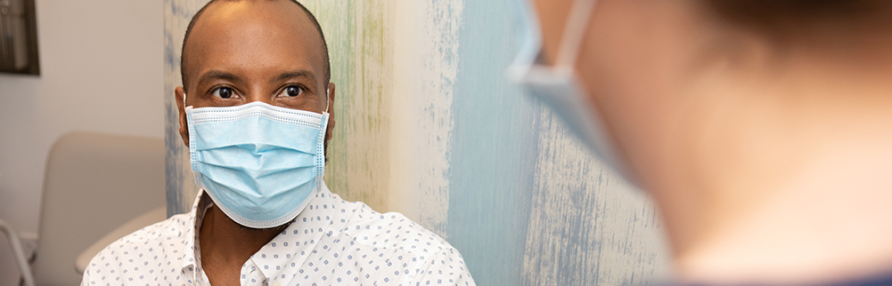 Patient wearing a mask talking to a provider.