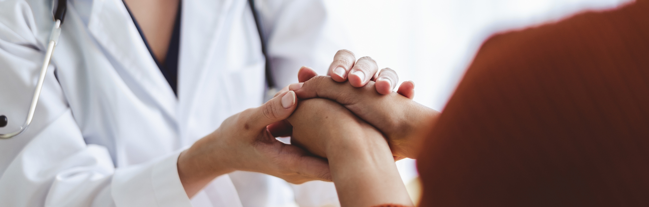 Close up of physician's hands holding a patient's hands