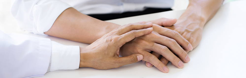 Close-up of doctor holding a patient's hands.