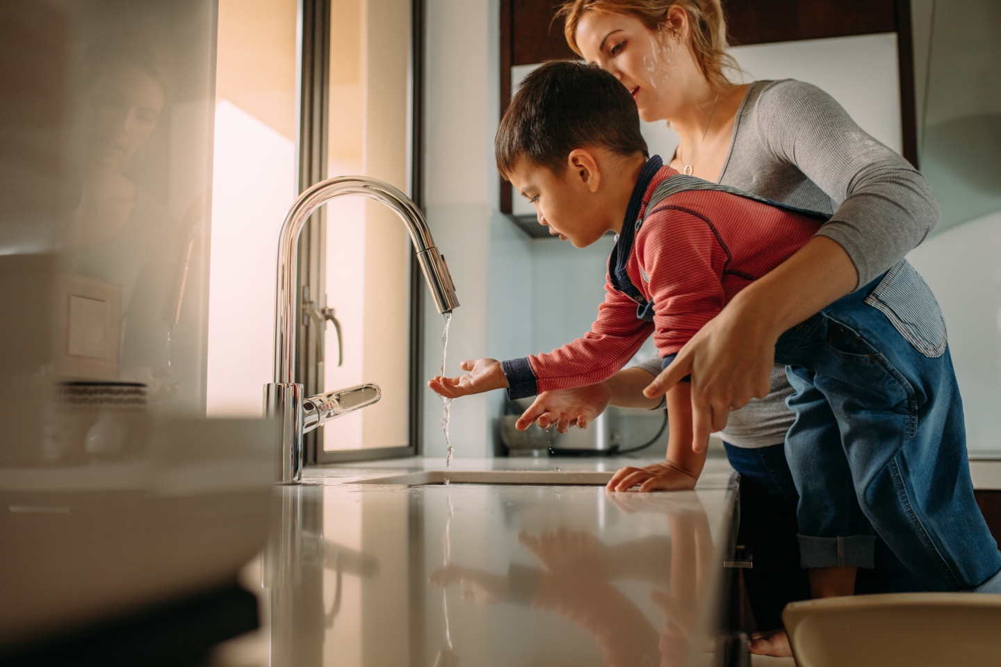 Mother helping son wash his hands at a sink