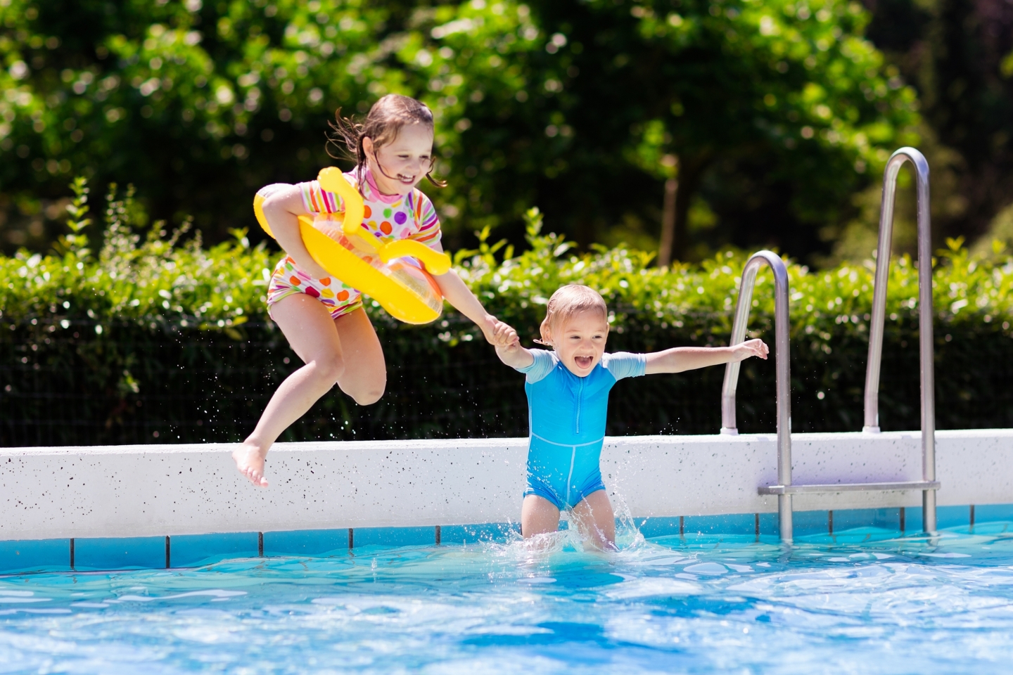 Girls jumping into a swimming pool