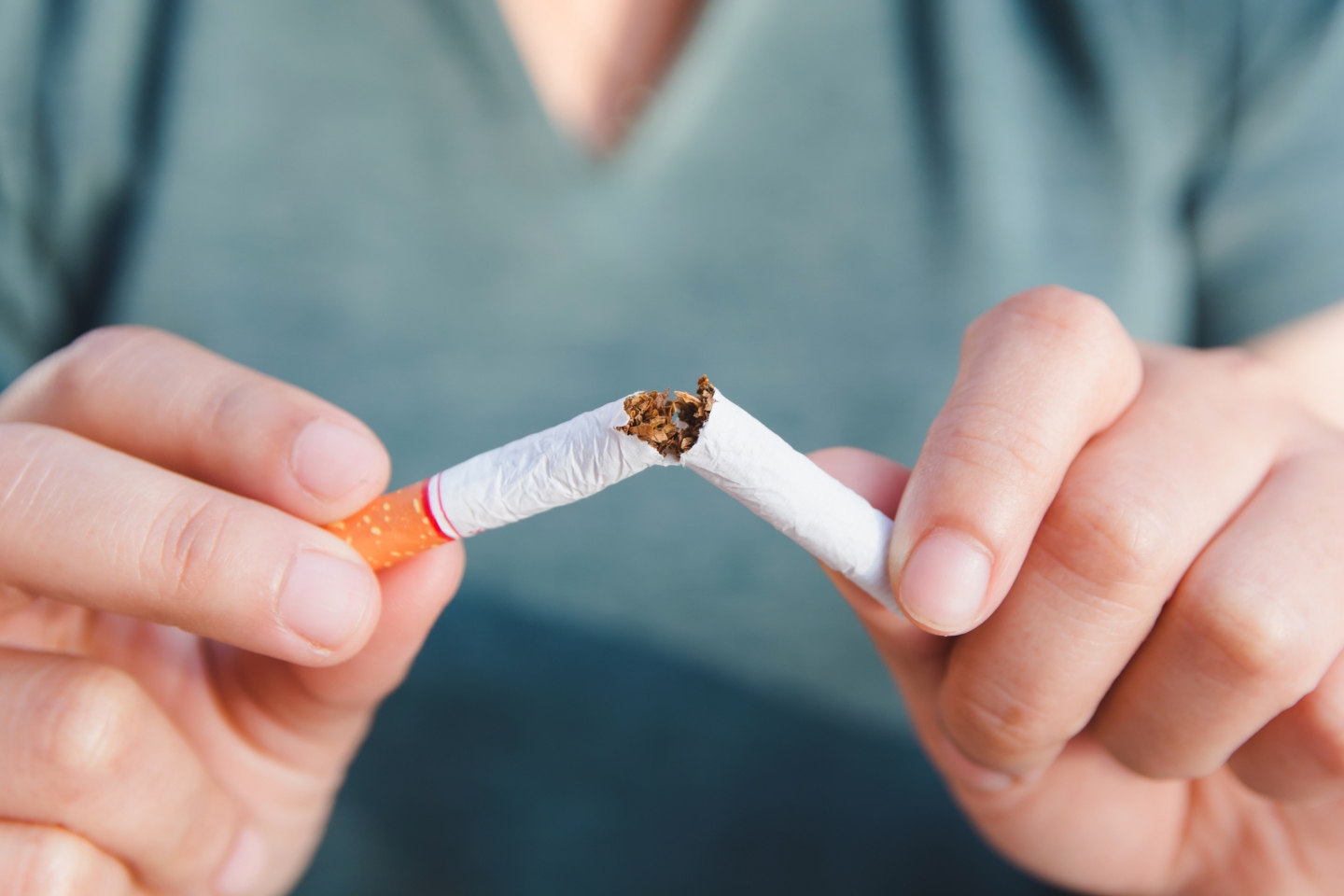 Person breaking a cigarette in half.