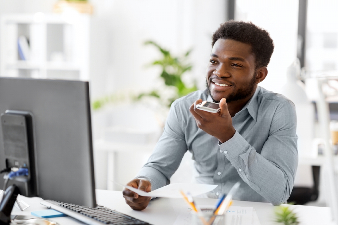 man at his computer speaking into phone