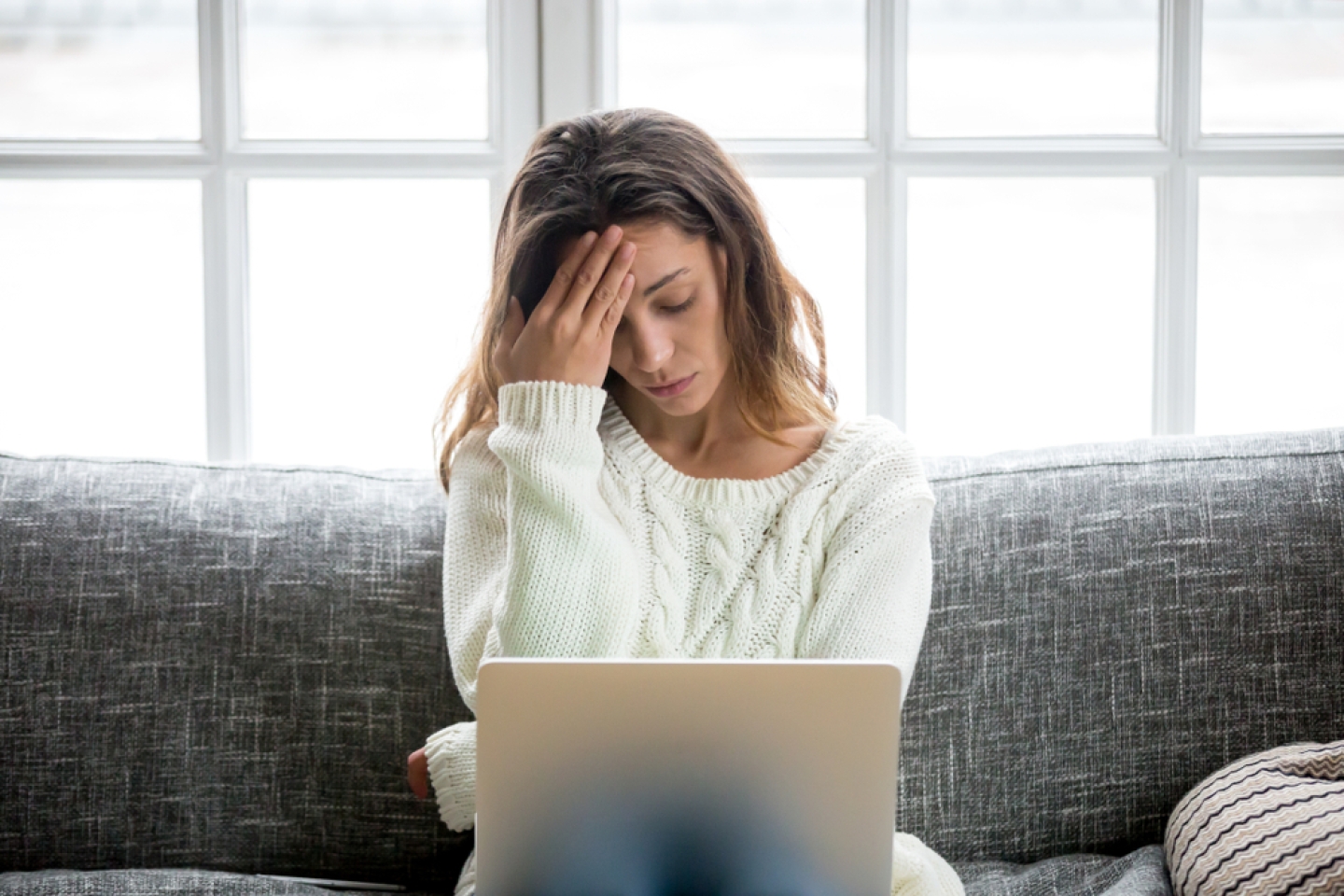 Frustrated sad woman feeling tired worried about problem sitting on sofa with laptop