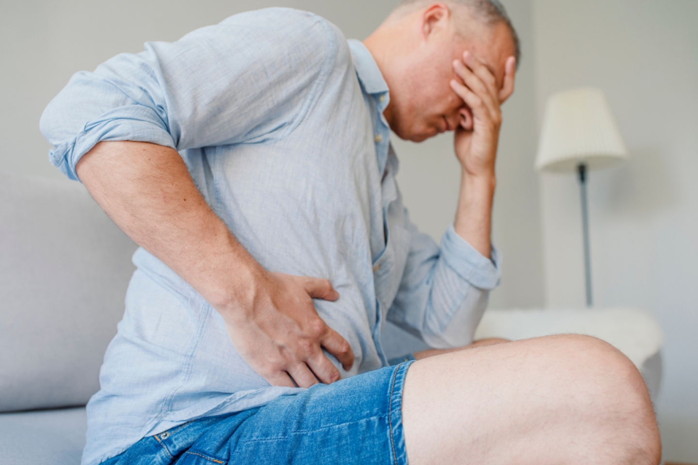 man hugging his belly and keeping eyes closed.