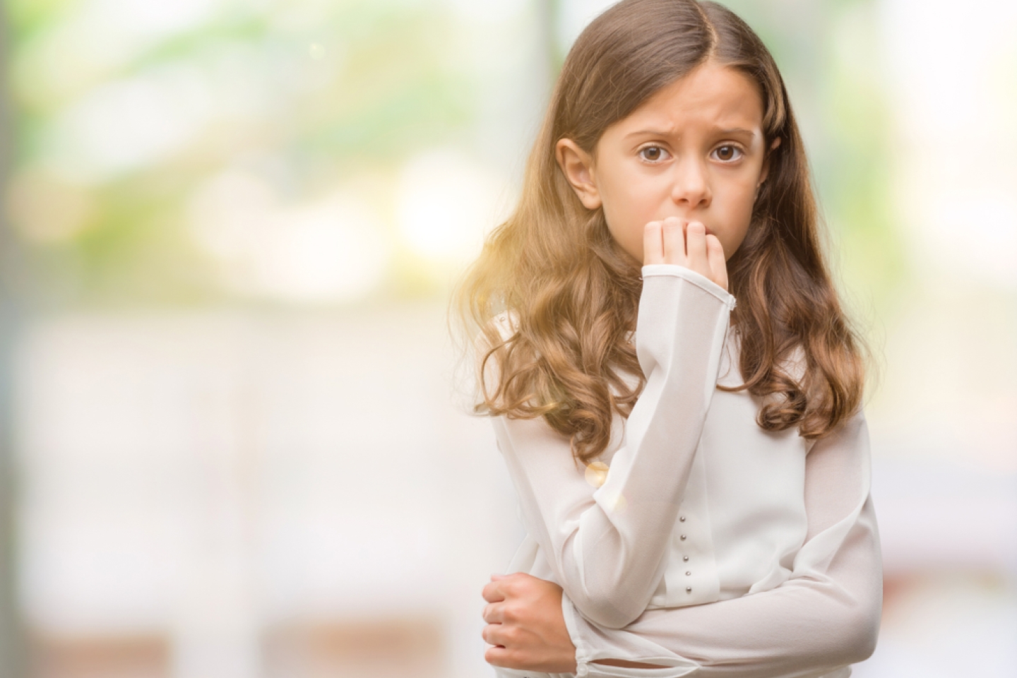 Brunette hispanic girl looking stressed and nervous with hands on mouth biting nails. Anxiety problem.