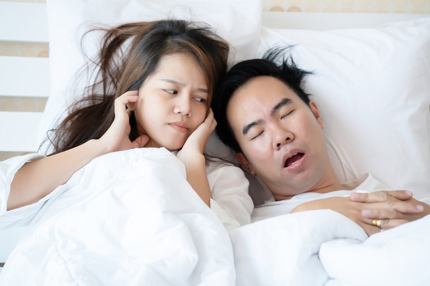 Couple on bed with white mattress Man snoring loud makes women feel annoyed.