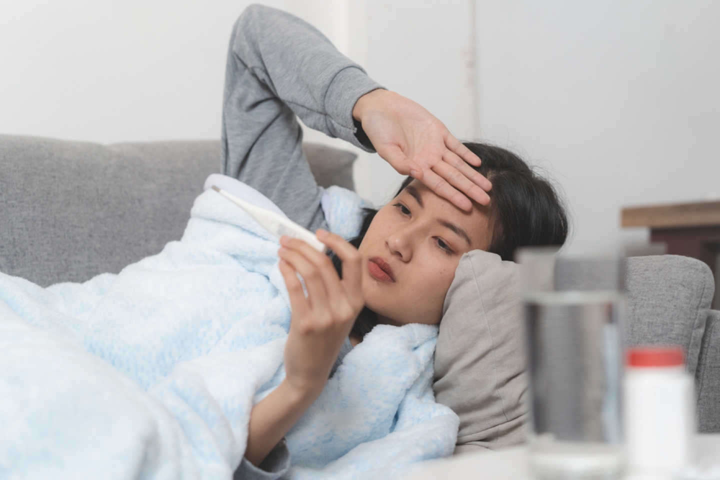 Woman measuring temperature her body on the bed. person got fever lying on the sofa.