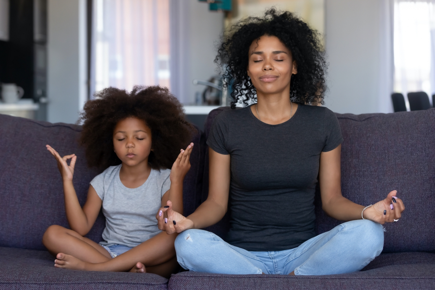 mom and daughter meditating on couch