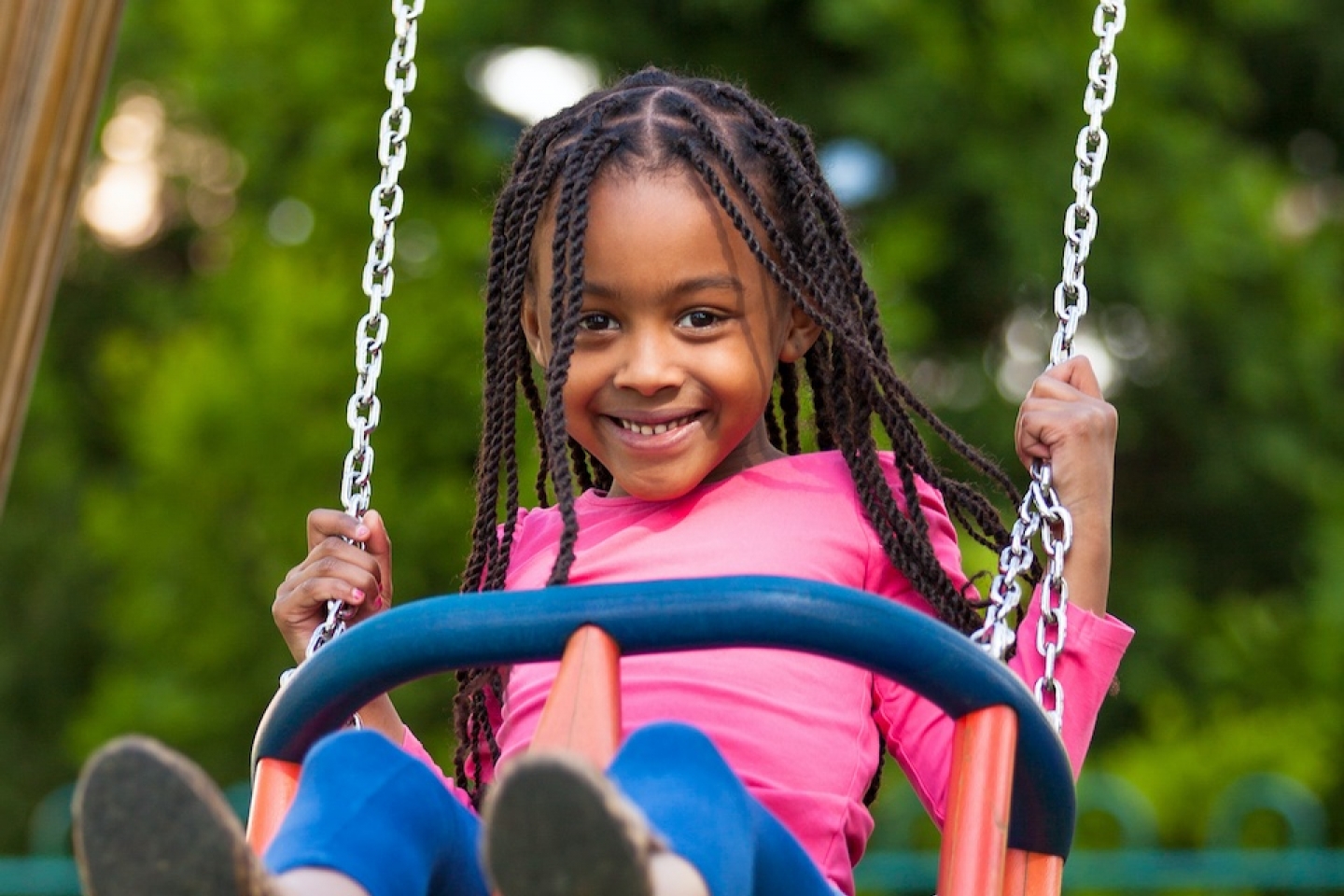 young black girl playing on swing in the park