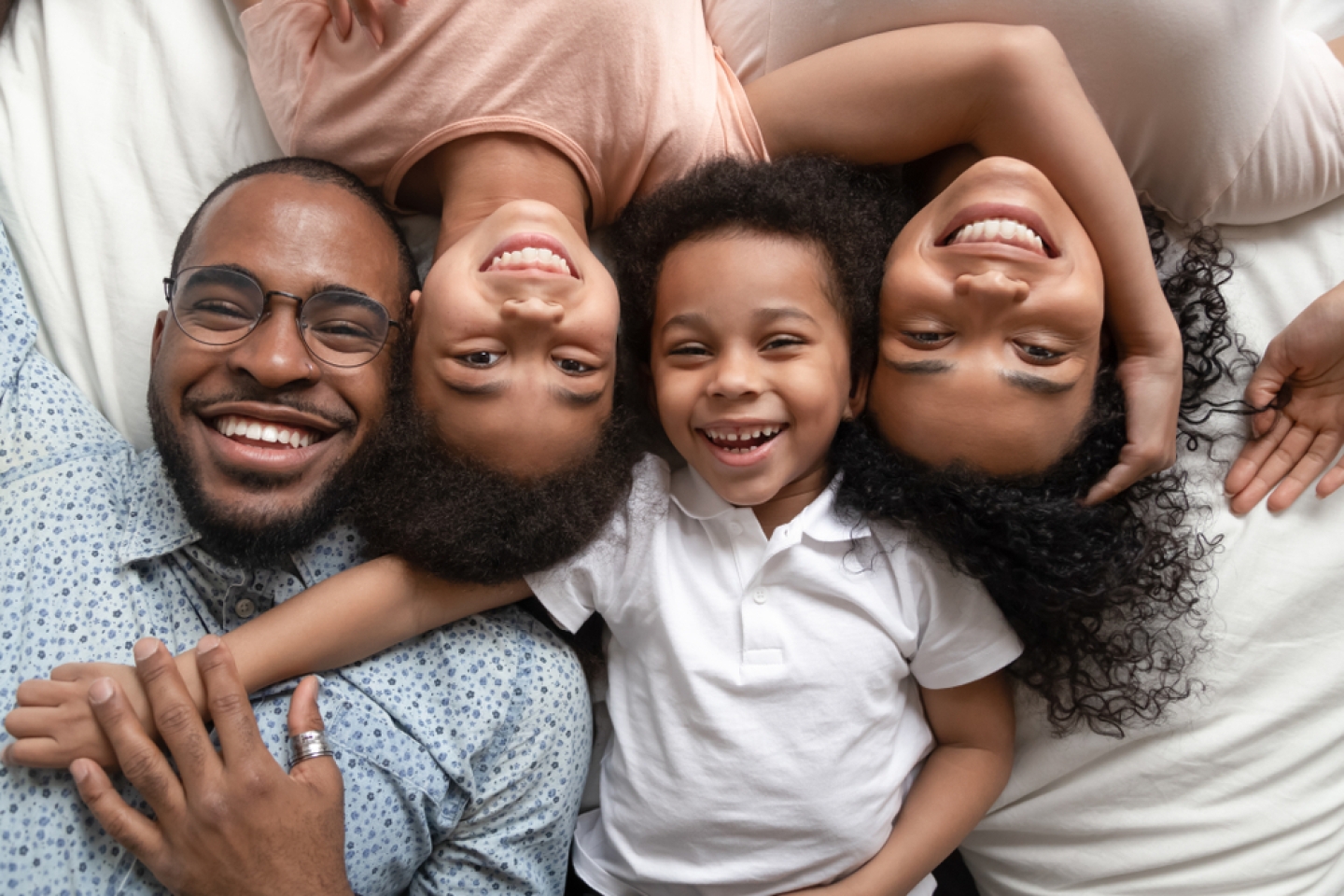 smiling african american dad mom and little kids bonding looking at camera