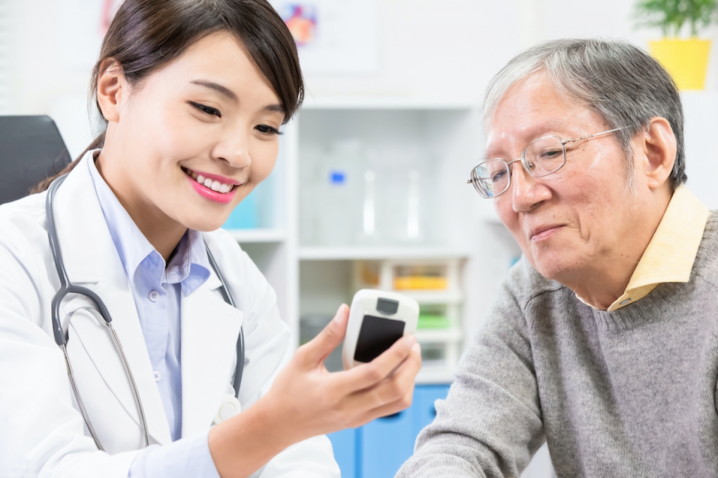 doctor reviews blood sugar monitor with older patient