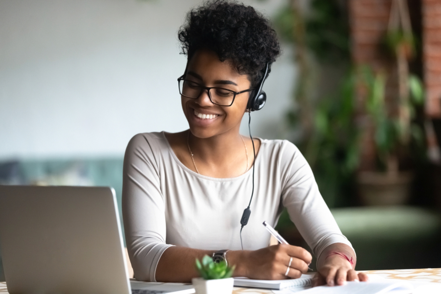 young woman in earphones work study using computer write in notebook