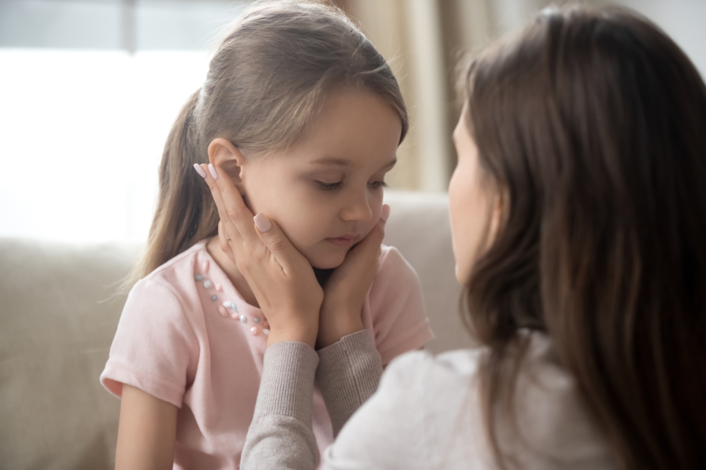 Loving young mother touching upset little daughter face, expressing support,