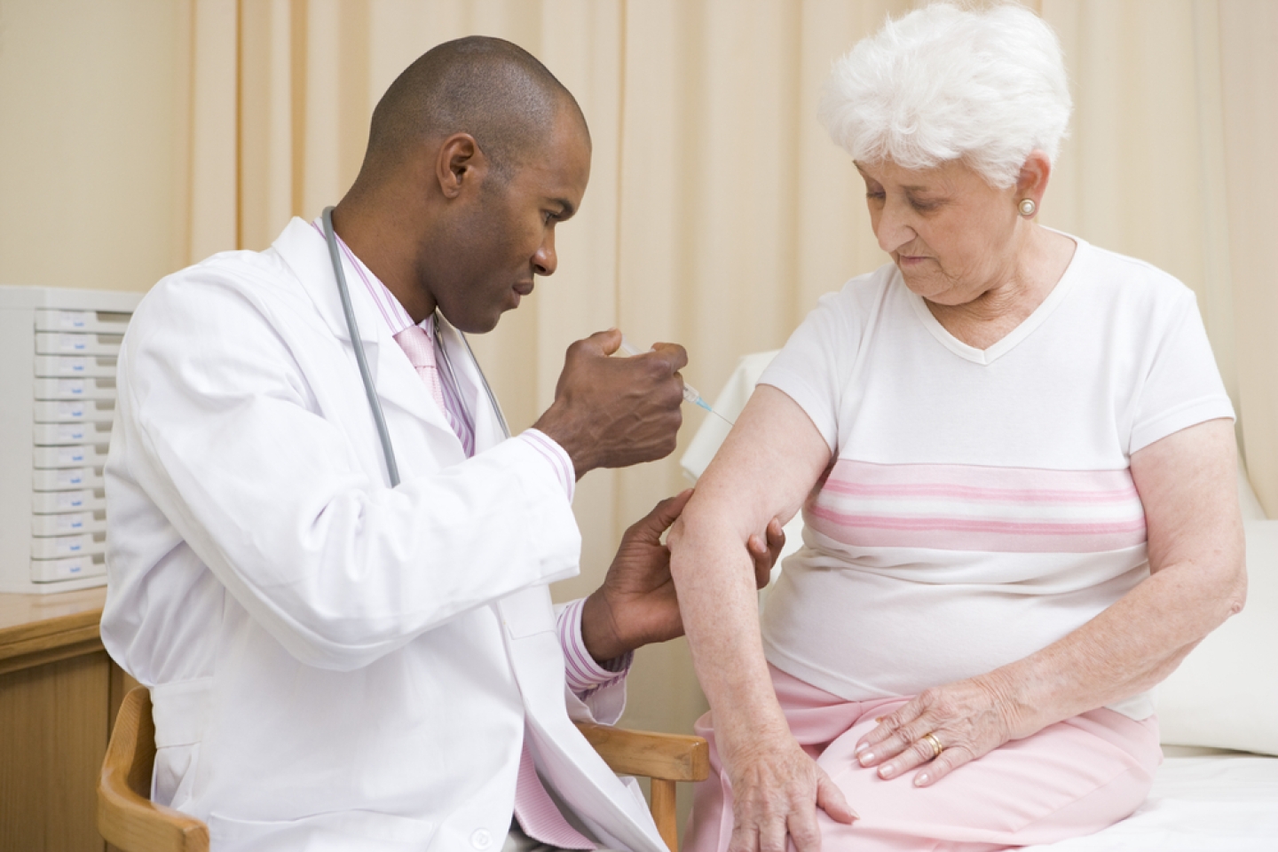 Doctor giving needle to woman in exam room