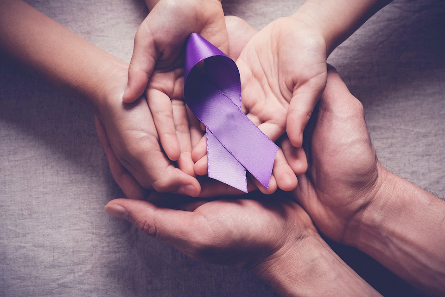 hands around purple ribbon