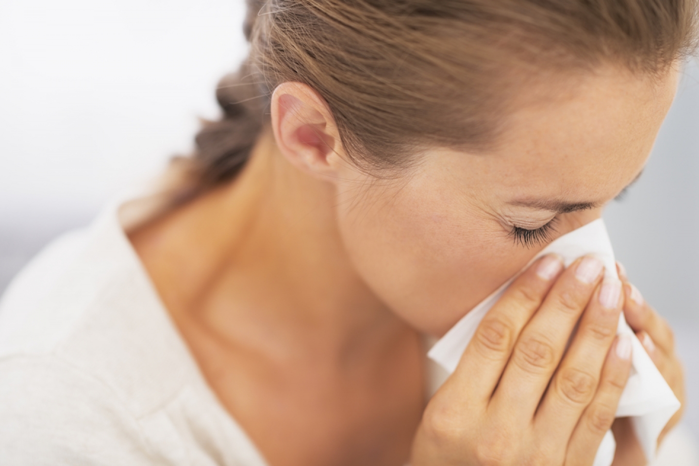 woman sneezing into tissue