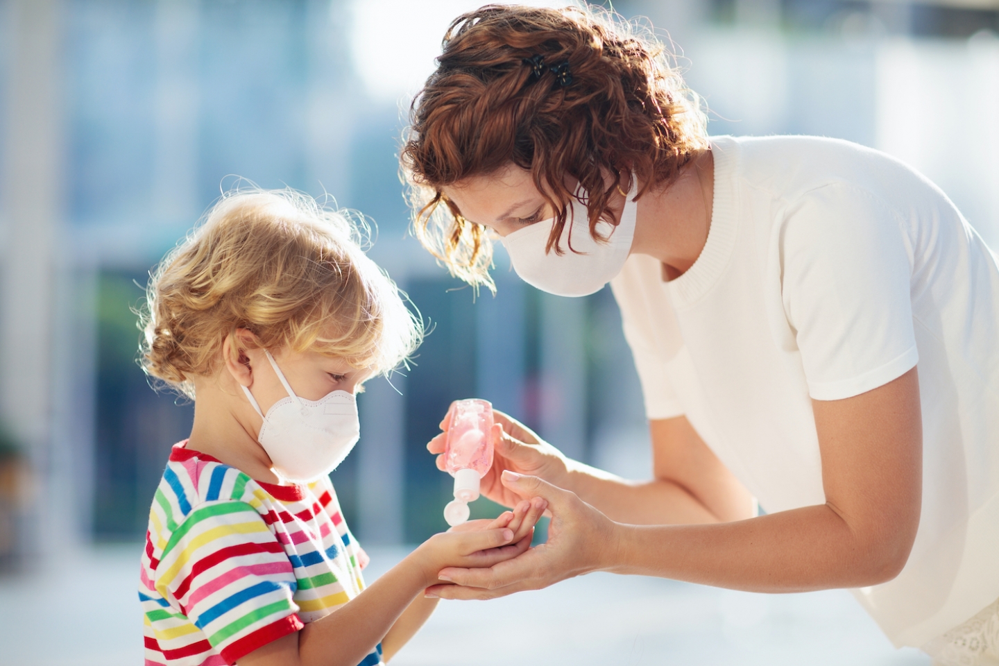 Mom and Son with masks on putting on hand sanitizer