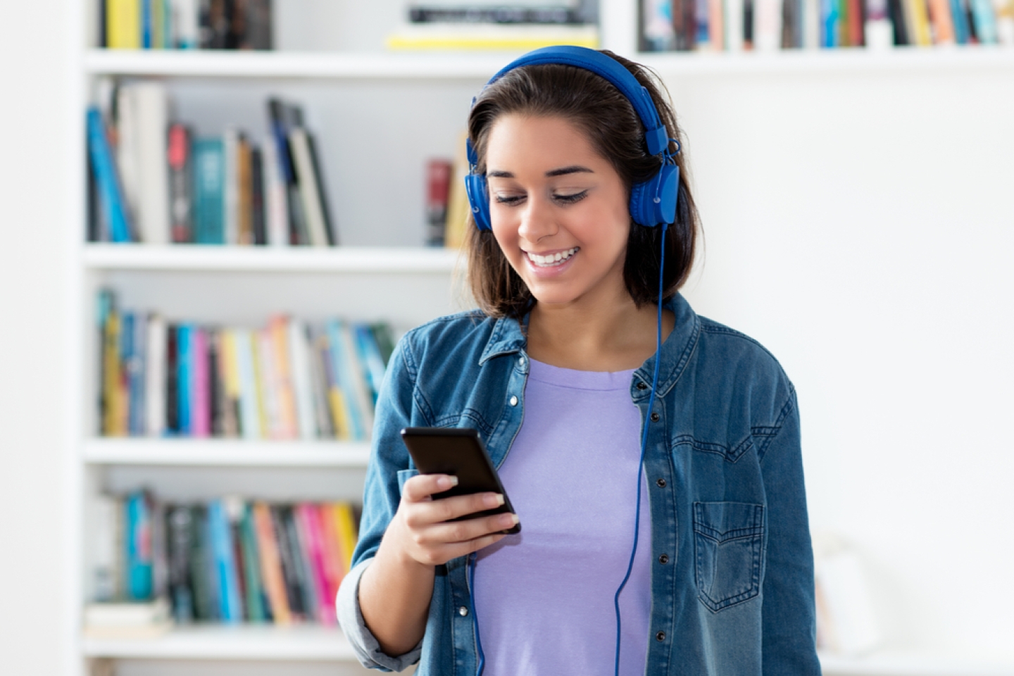 young adult woman listening to podcast indoors at home