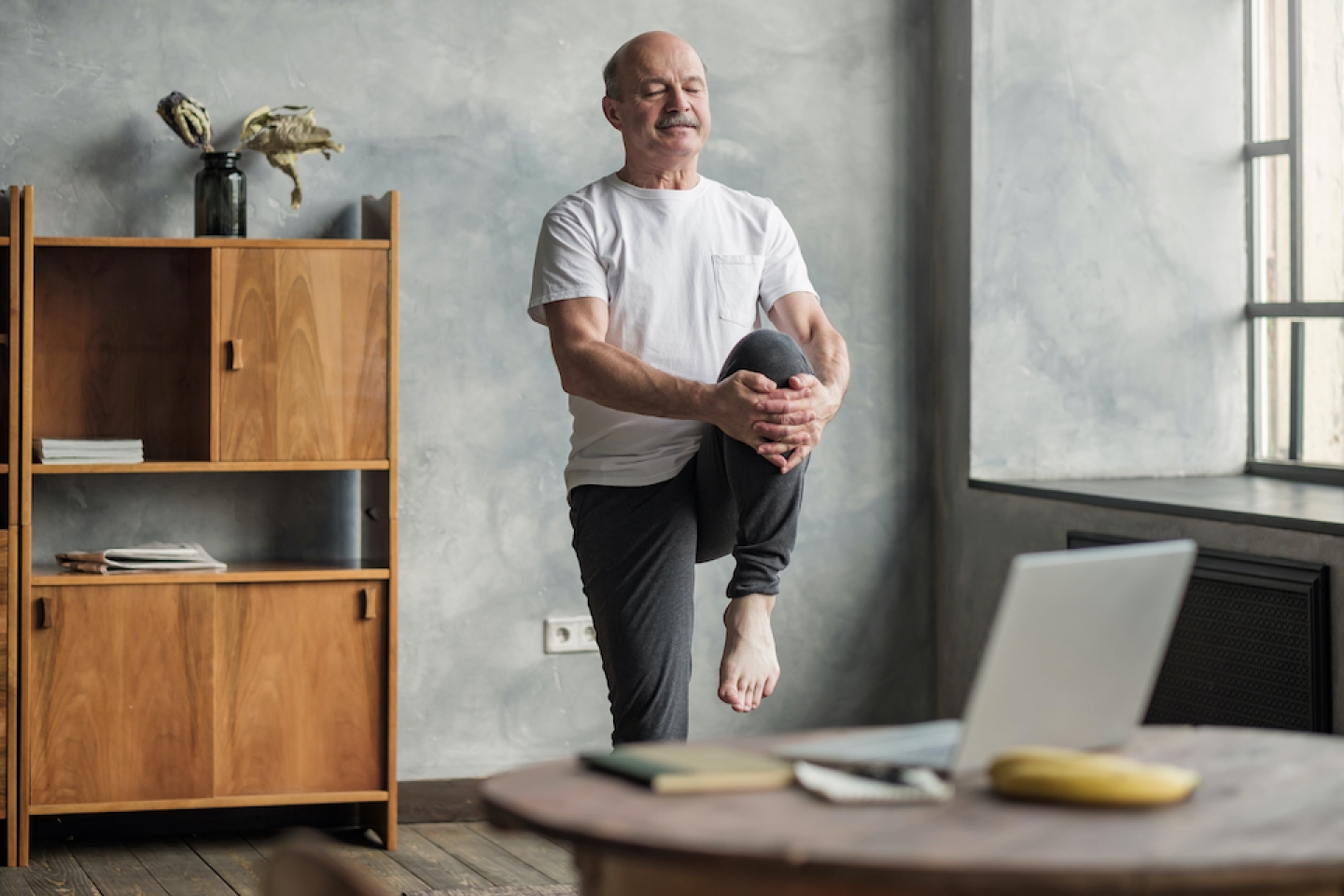 older man stretches at home