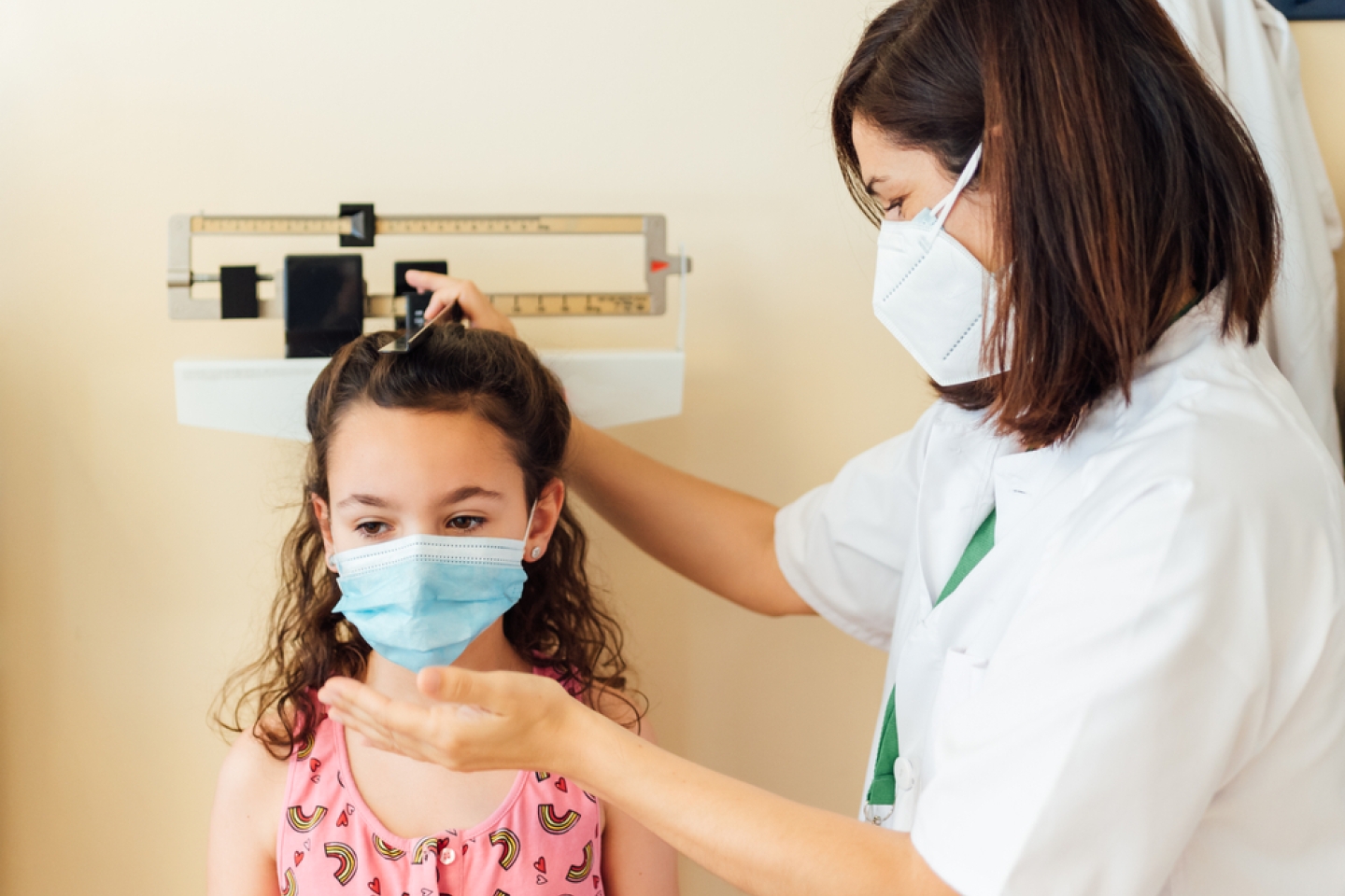  The pediatric doctor measures and weighs the child in the clinic office.