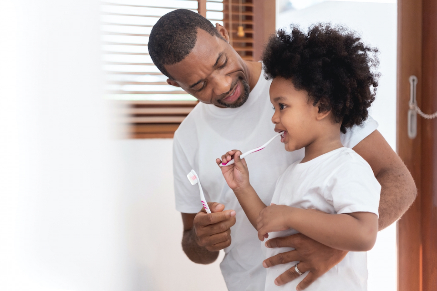 Black dad and daughter brushing their teeth