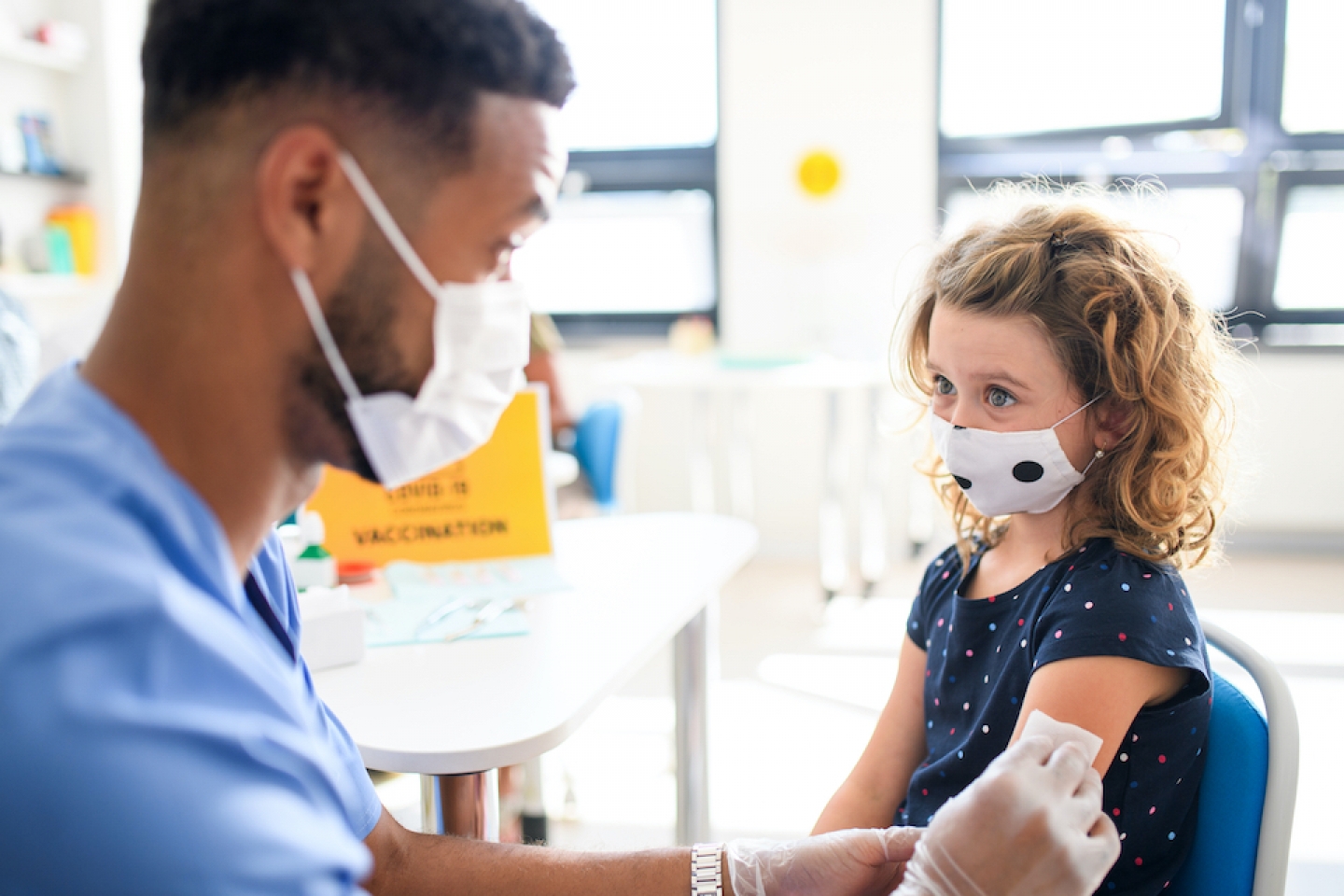 black doctor giving younger patient vaccine shot