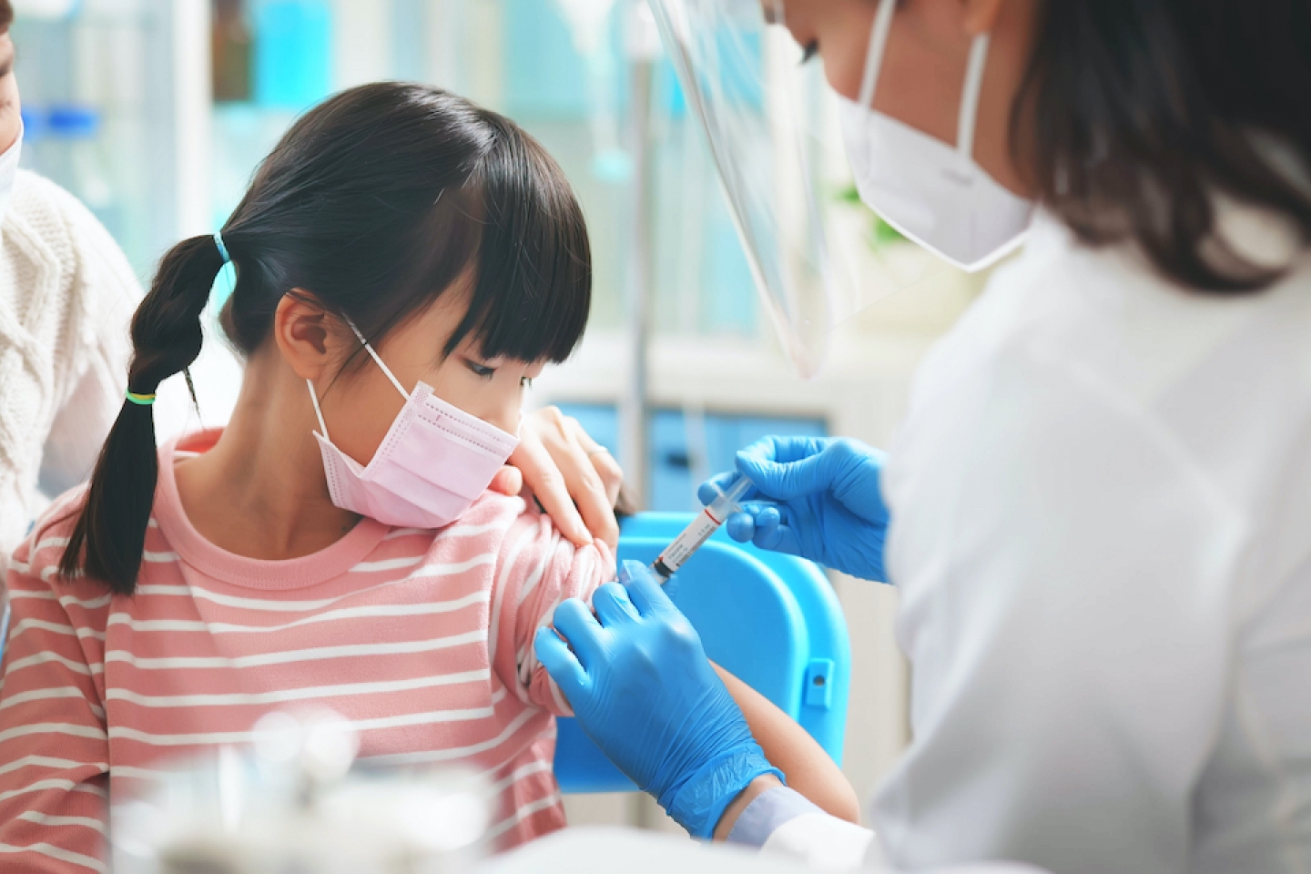 younger asian girl receives vaccine shot