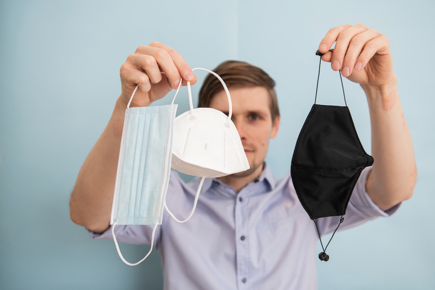 man holds up different masks