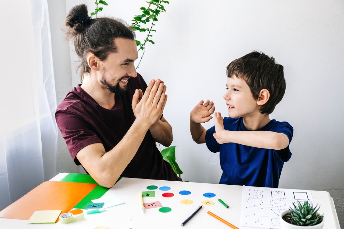 Happy autism boy during therapy with school counselor, learning and having fun together