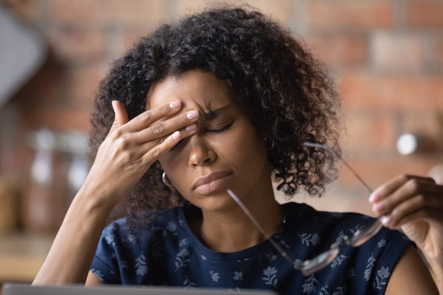 Frustrated black female freelancer overworked by computer feel headache migraine take off eyewear rub nose bridge.
