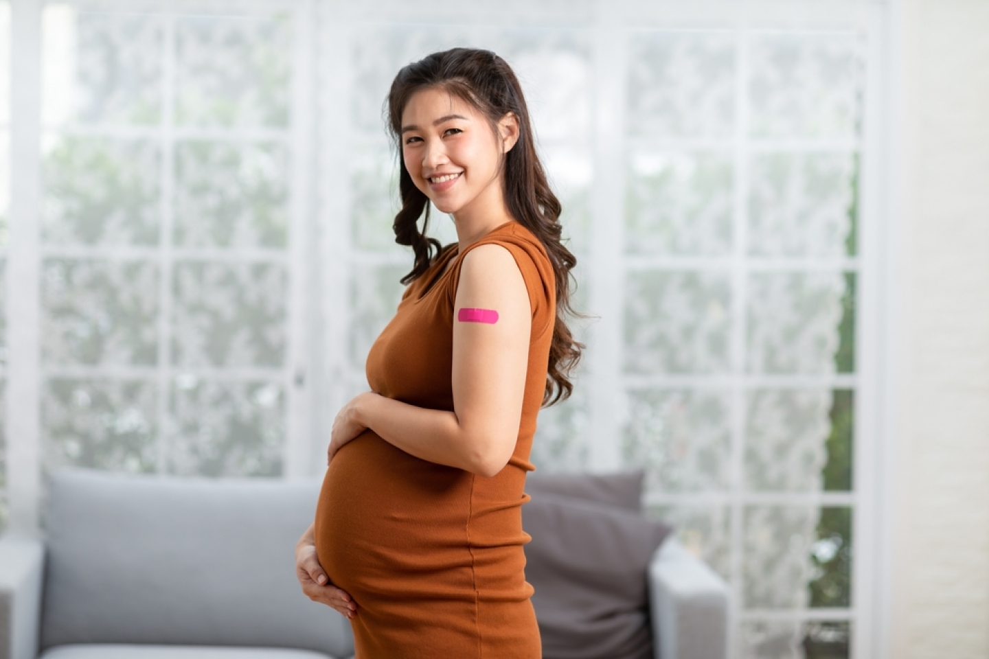 Happy pregnant woman wearing bandage after receiving vaccine.