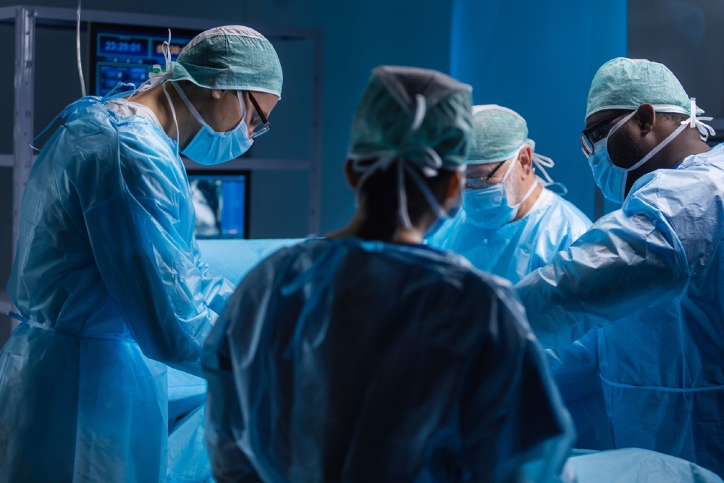 Multiracial team of professional medical surgeons performs the surgical operation in a modern hospital. Doctors are working to save the patient. Medicine, health, cardiology and transplantation.