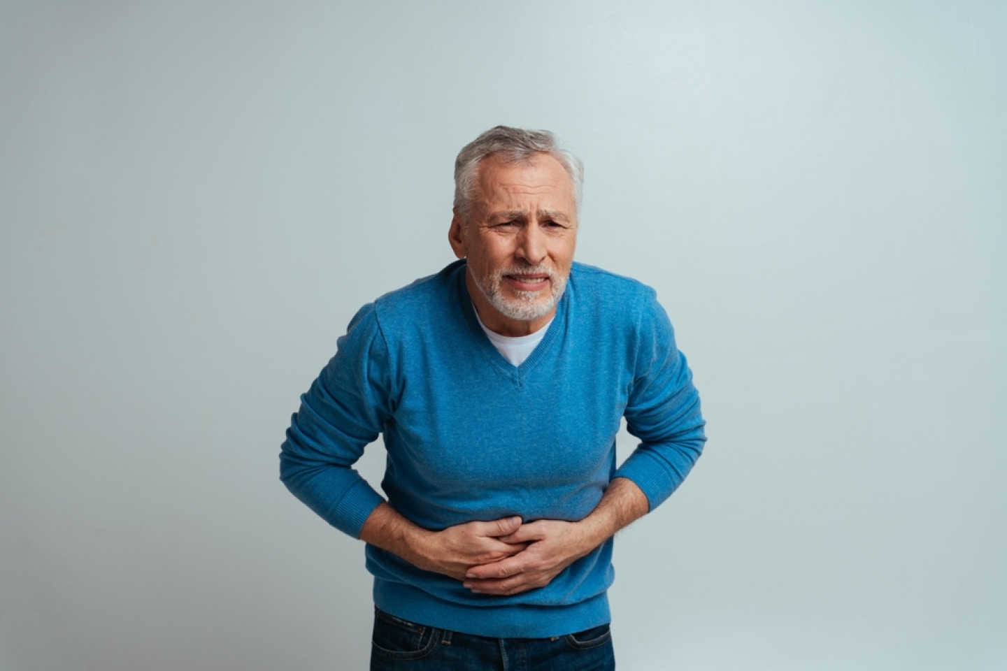 Handsome senior isolated on grey background. Old man feeling pain. Concept about the third age and seniority