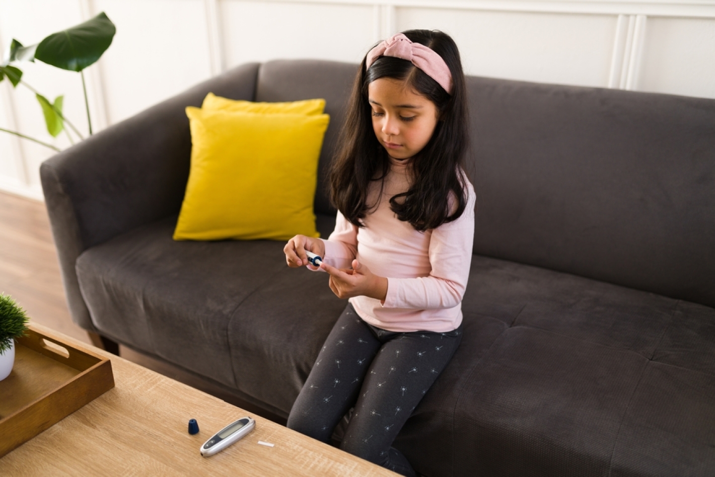 Young girl with diabetes type 1 checking her glucose levels with a blood test monitor at home