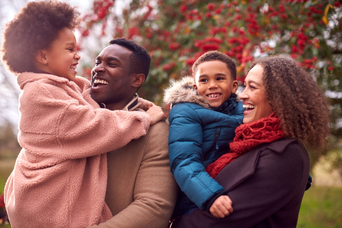 Parents Carrying Children As Family Enjoy Fall Or Winter Walk In Countryside