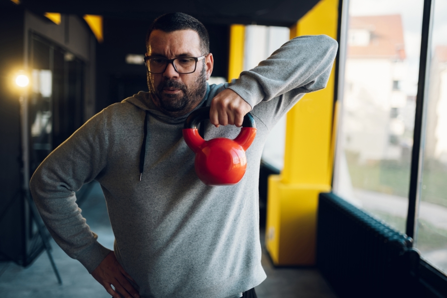Obese middle aged men training in the gym while using kettlebell. Overweight man trying to lose weight. Warming up.