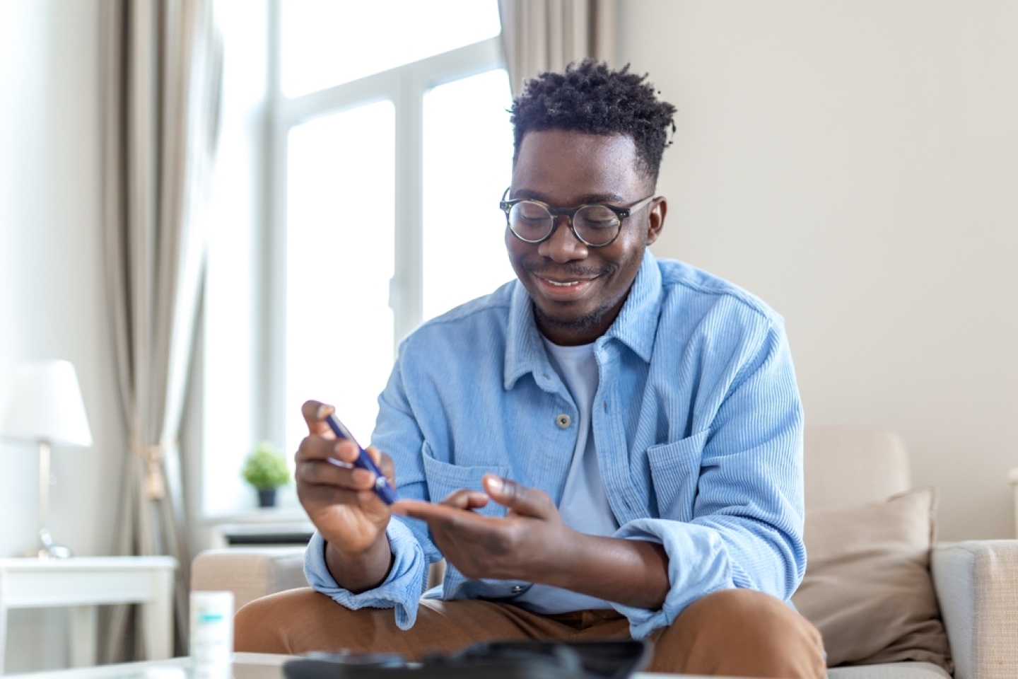 Man checking blood sugar on couch