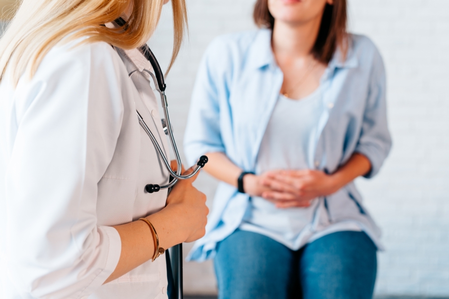 a woman in consultation with a doctor with abdominal pain