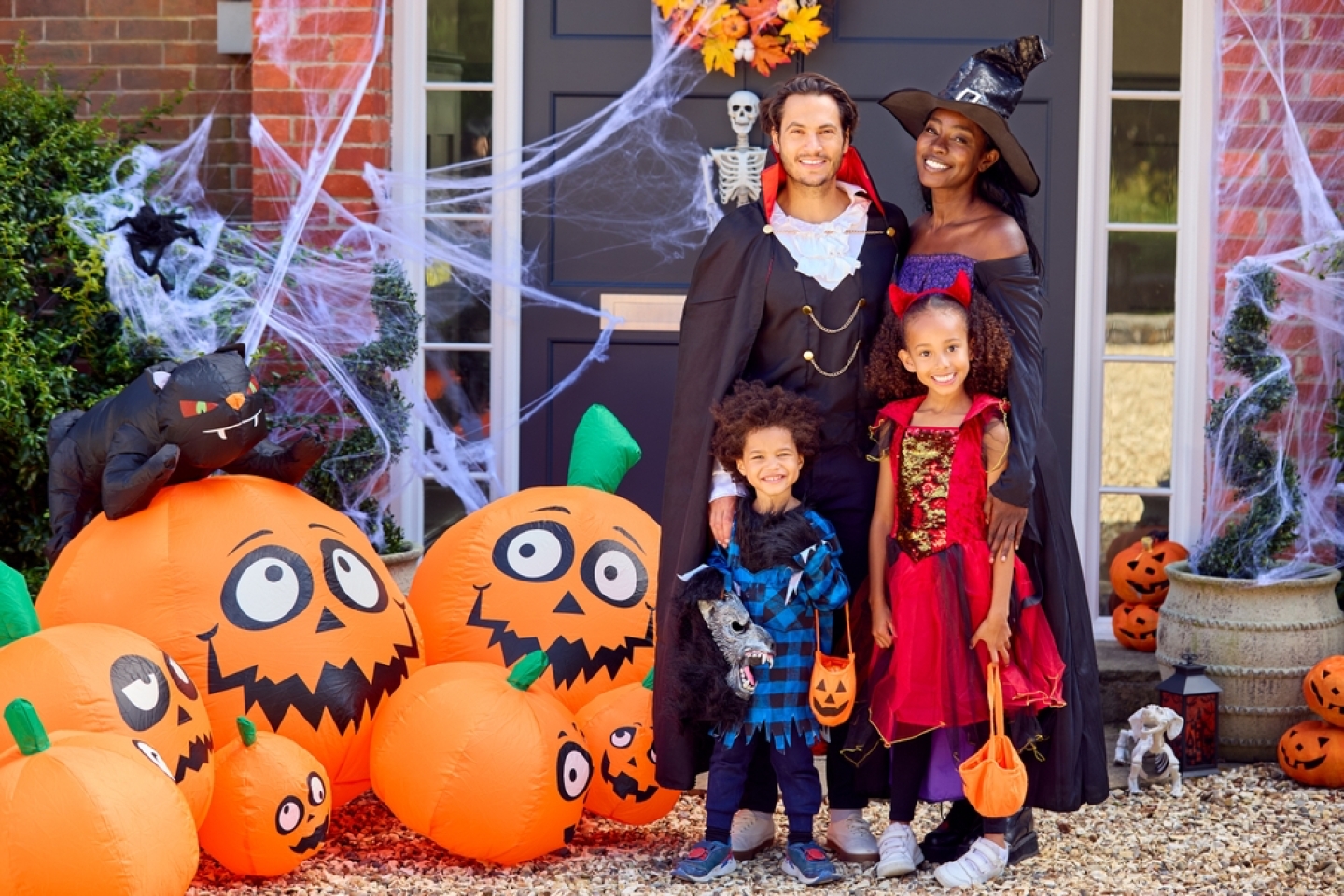 Portrait Of Family Dressed Up For Halloween Outside House Ready For Trick Or Treating