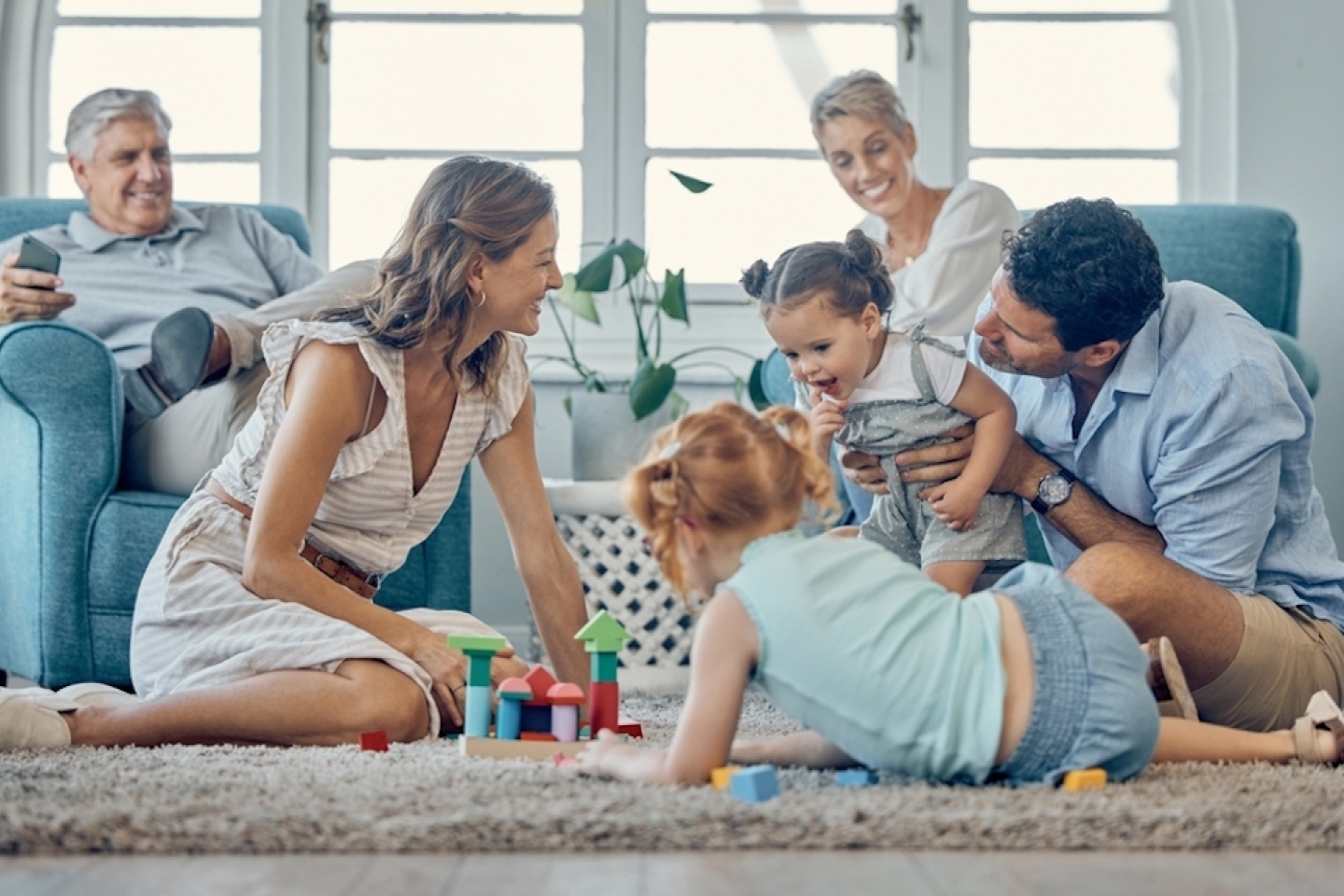 Family, grandparents and children play on carpet together and relax for learning, teaching and home language development.