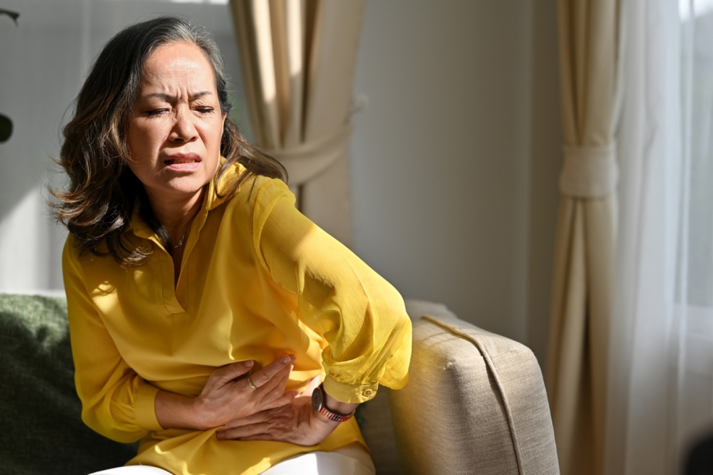 Senior woman holding belly, feeling discomfort,