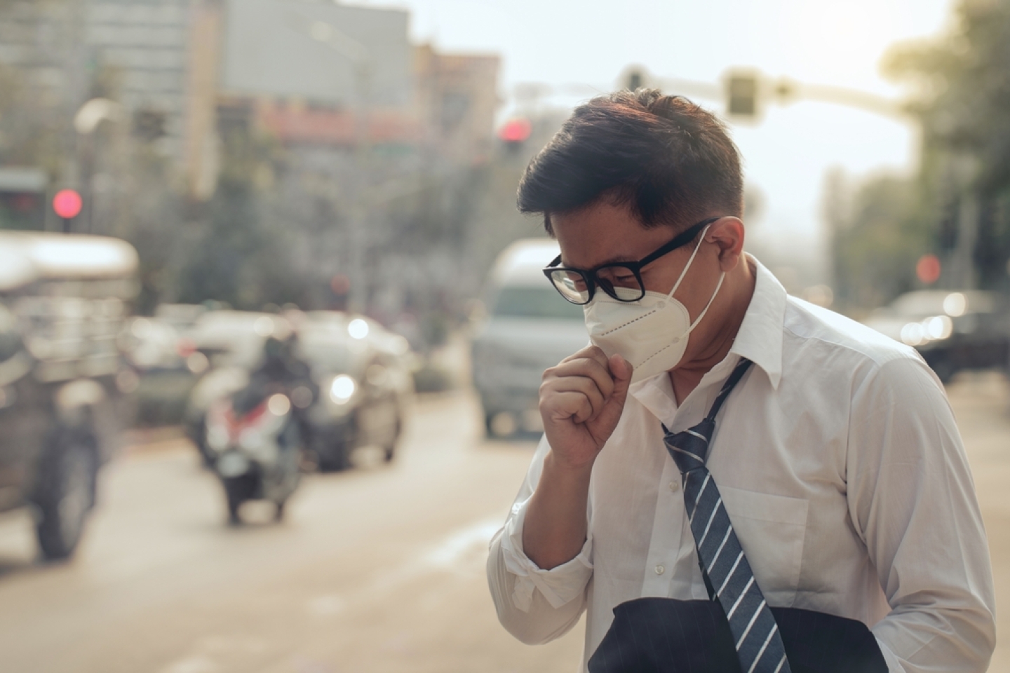 Business man wearing a mask and coughing on the street.