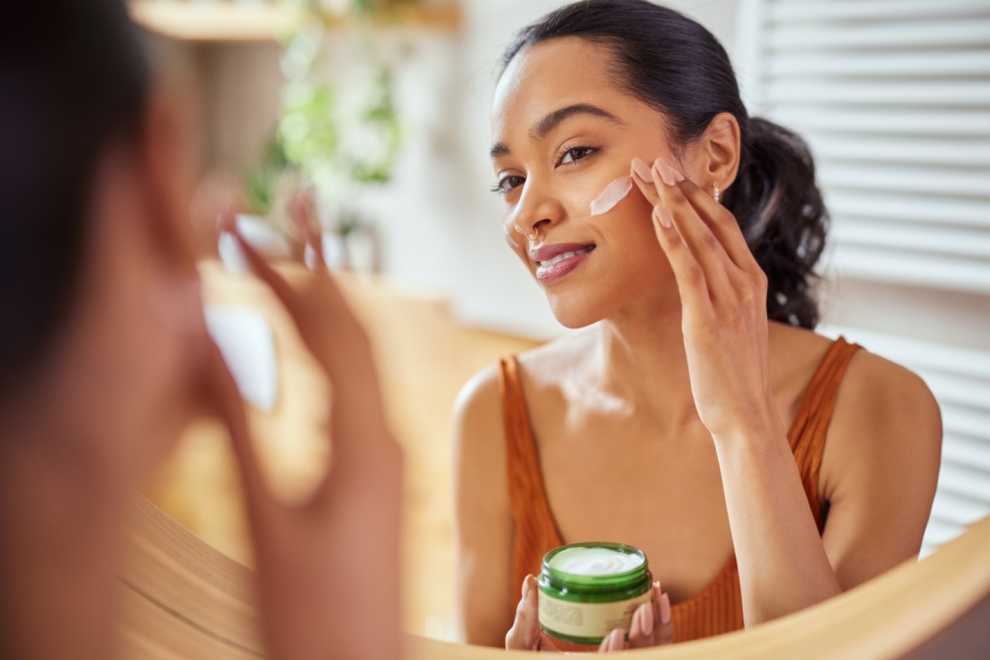 Woman caring of her beautiful skin on the face standing near mirror in the bathroom.