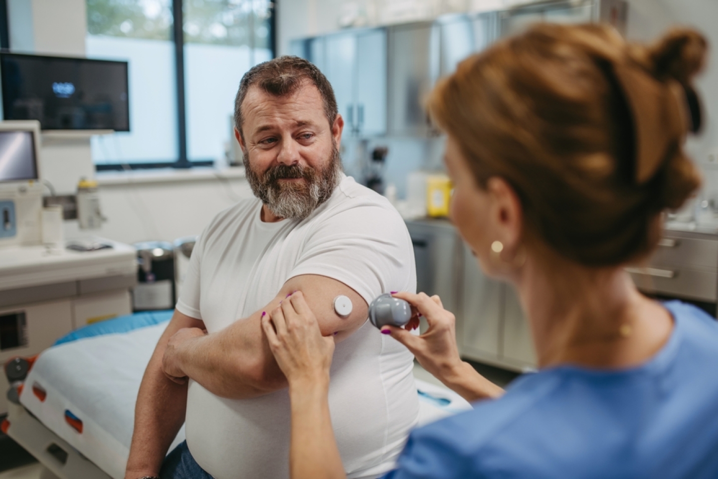 Doctor applying a continuous glucose monitor sensor on patient's arm