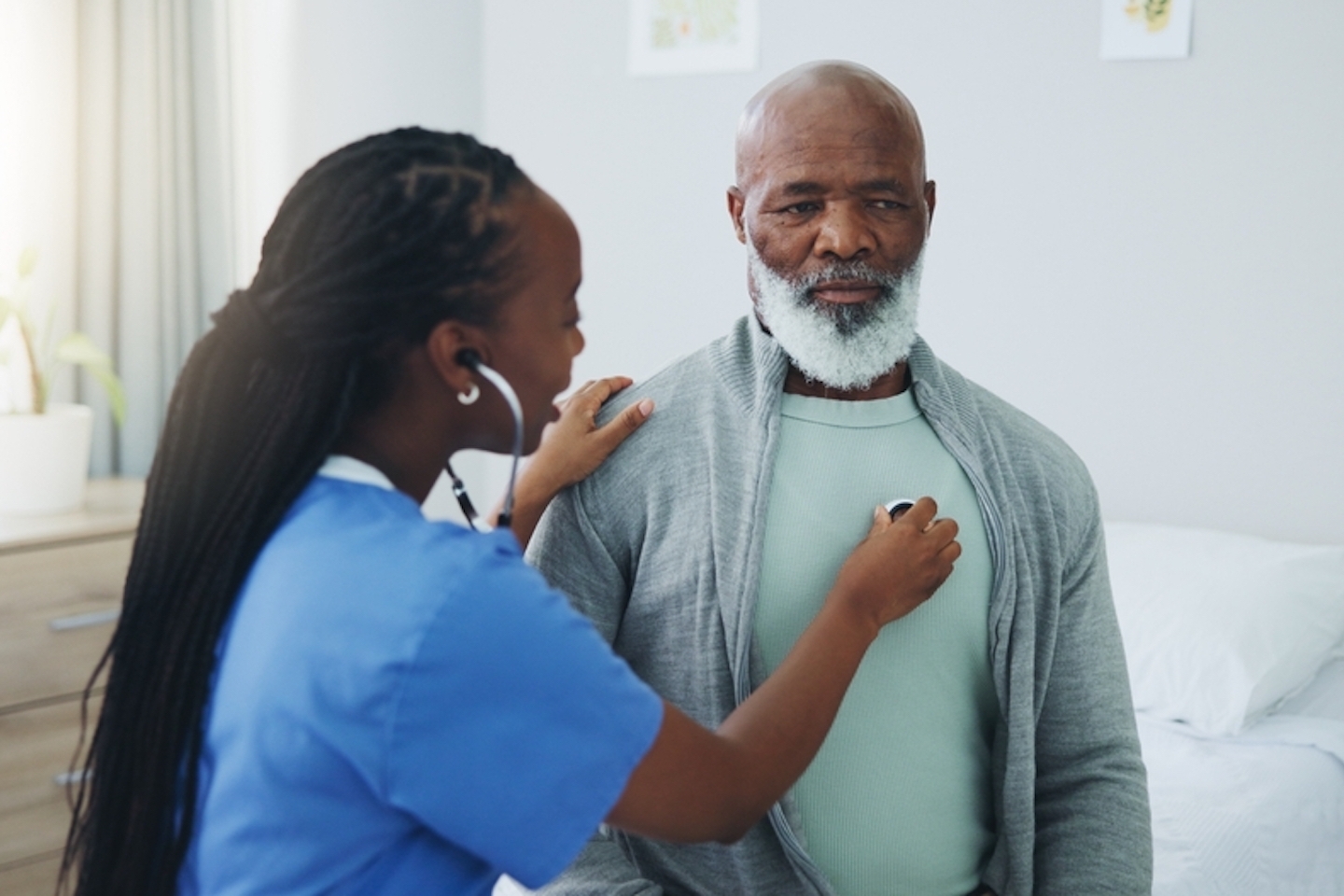 Senior, man and nurse with listening on stethoscope for heartbeat assessment or cardiovascular health on bed. Elderly patient, doctor and cardiology in hospital for lung disease or chest infection