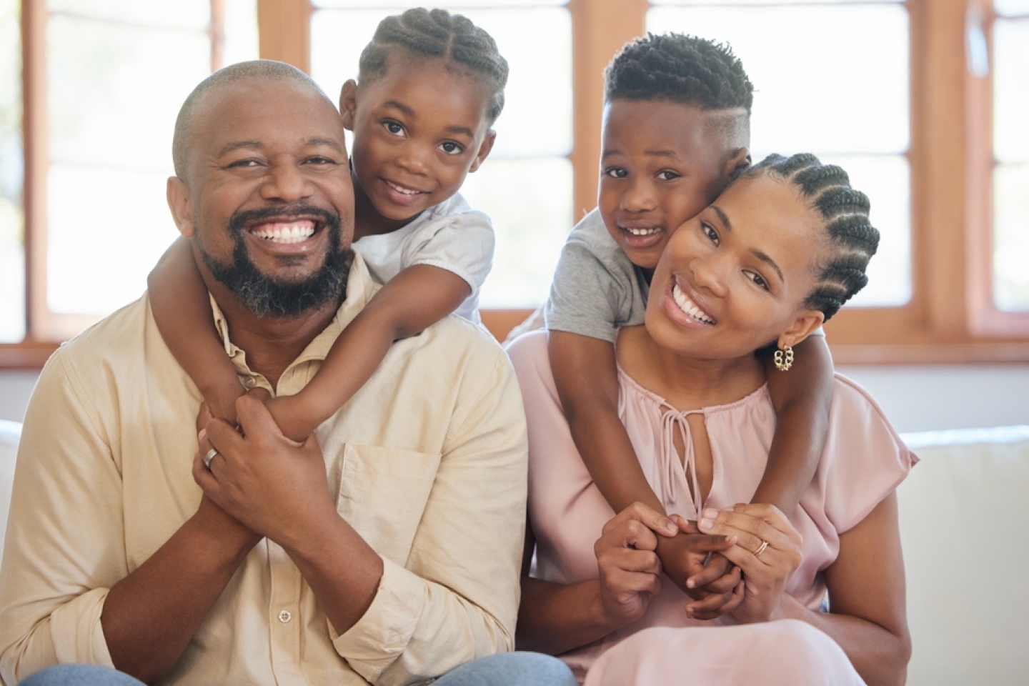 Hug, happy family and portrait in home on weekend with love for mom, dad and kids on couch. African man, woman and children on sofa for care, support and trust or bond together with smile and pride