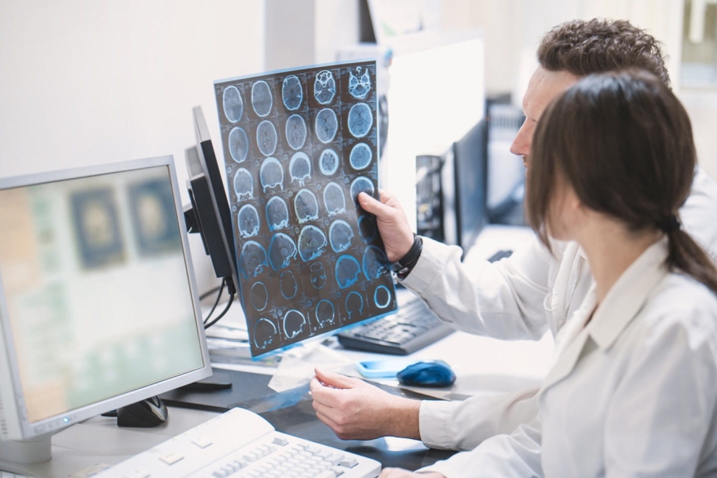 two doctors man and woman doctor examine an MRI image of the brain in an MRI room.